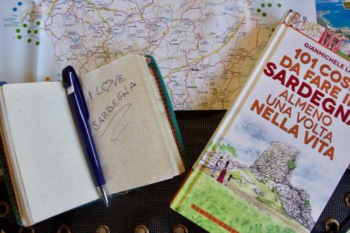 two books and a pen on top of a map at Casa THE NEST - Il Nido sul Mare in Badesi