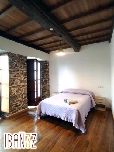a bedroom with a bed and a stone wall at Ibañez 3 in Ribadeo
