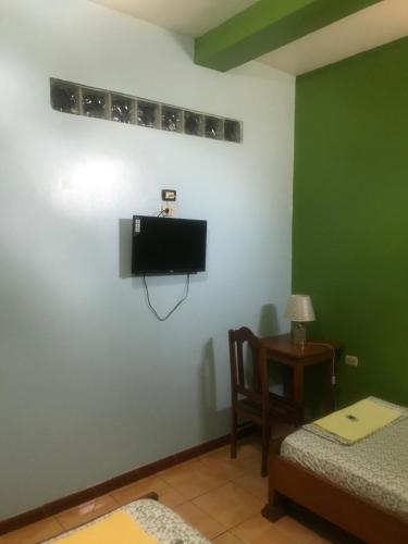 a room with a tv and a bed and a table at Amazon Dream Hostel with AC and Starlink in Iquitos