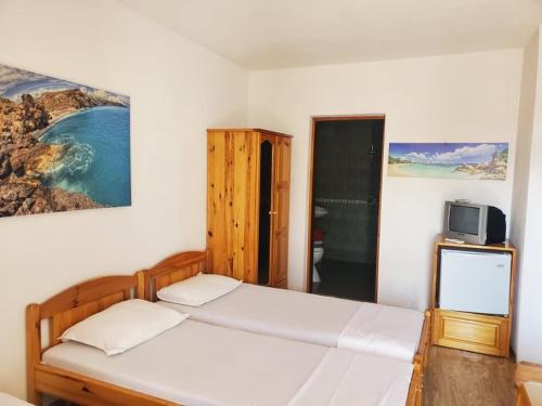 a bedroom with two beds and a tv on the wall at Guest House Dzhegosh in Primorsko