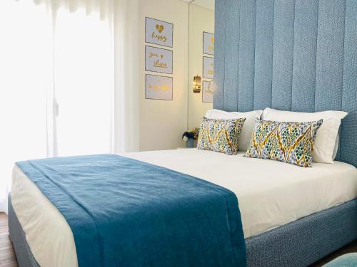 a bedroom with a large bed with a blue wall at Alojamento Batata in Nazaré