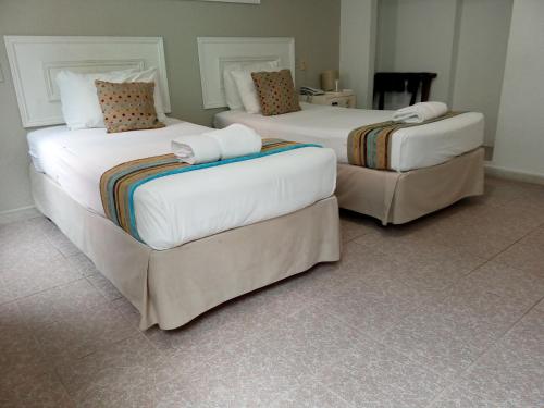 two beds in a hotel room withskirts at San Marco Hotel Curacao & Casino in Willemstad