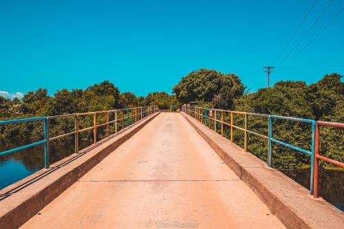 a bridge over a river with trees in the background at Pousada dos Corais in Itaúnas