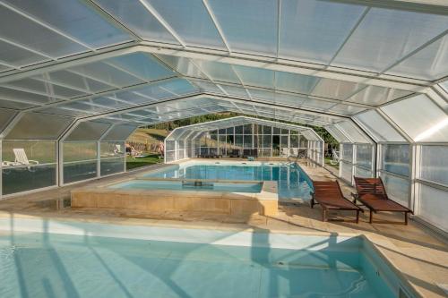 a swimming pool with two chairs and a glass house at Montesinho Eco-Resort in Bragança