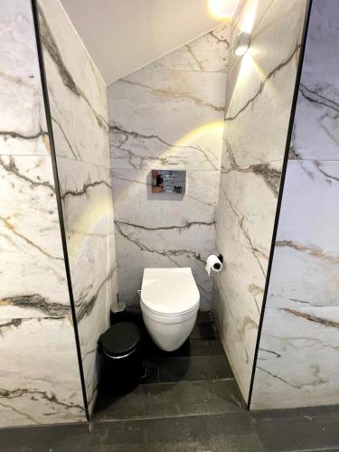 a bathroom with a white toilet and marble walls at Agora LX Studios & Suites in Thessaloniki