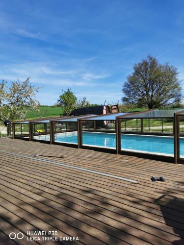 une terrasse en bois avec une clôture autour d'une piscine dans l'établissement Gîte spacieux avec accès SPA privatif et piscine de 2 à 10 voyageurs, à Brassac