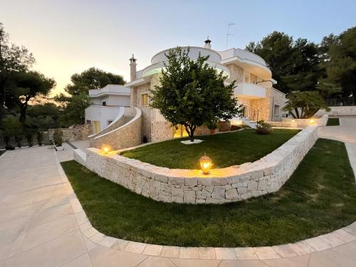 a large house with a stone wall and a yard at ESSENZA in Massafra