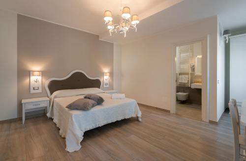 a white bedroom with a bed and a chandelier at ESSENZA in Massafra