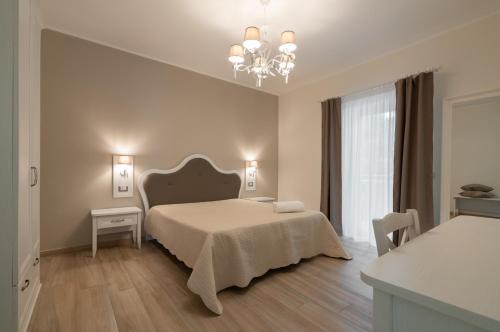 a white bedroom with a bed and a chandelier at ESSENZA in Massafra
