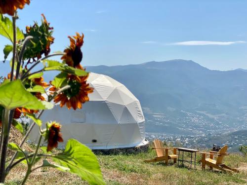 a white tent on top of a hill with flowers at Yenokavan Glamping in Ijevan