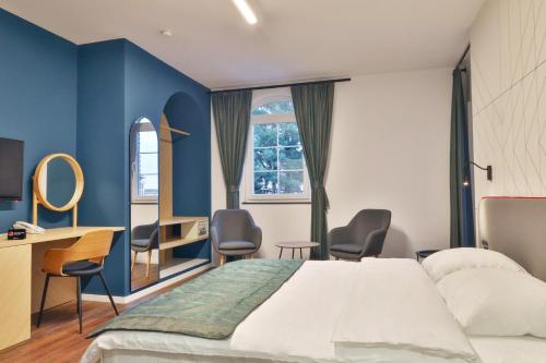 una camera d'albergo con letto, scrivania e sedie di Benelux Hotel a Pejë