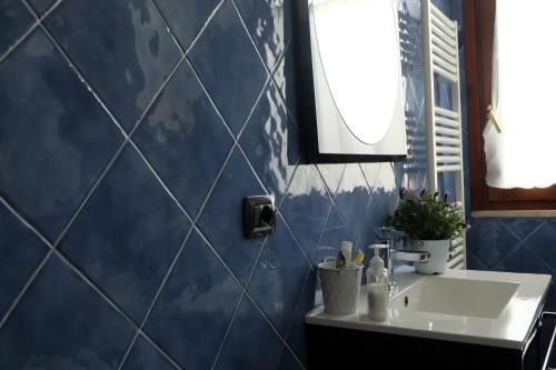 Baño de azulejos azules con lavabo y espejo en B&B Delle Fragole, en Medicina