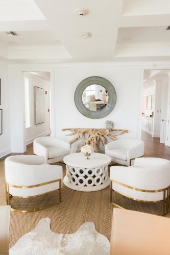 a living room with white furniture and a round mirror at Oyster Bay Boutique Hotel in Pensacola