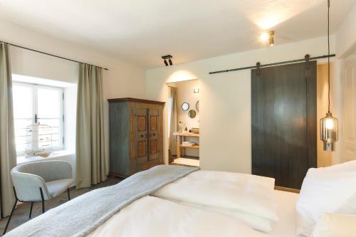 a bedroom with a bed and a chair and a window at Townhouse by Frauenzimmer in Abtenau