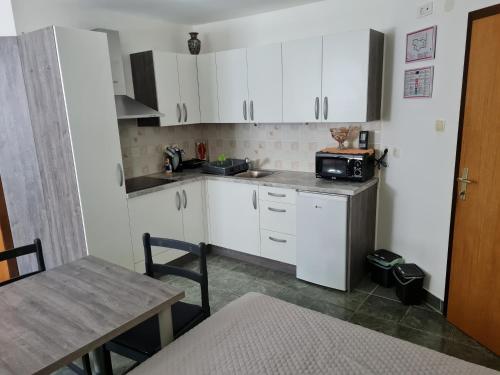 eine kleine Küche mit weißen Schränken und einem Tisch in der Unterkunft Apartma Juteršek 2+2 in Libeliče