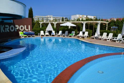 a large blue swimming pool with chairs and umbrellas at Akropoli Hotel in Golem