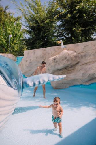 a little boy standing next to a shark in a water park at Camping Sènia Caballo de Mar in Pineda de Mar