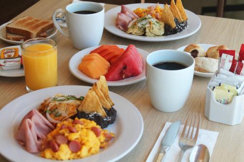 - une table avec des assiettes de produits pour le petit-déjeuner et du café dans l'établissement Holiday Inn Express Mérida, an IHG Hotel, à Mérida