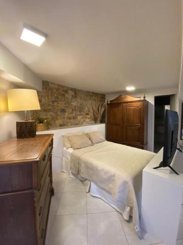 a bedroom with a bed and a desk with a television at SUÍTE DO ENCANTO - Centro Petrópolis in Petrópolis