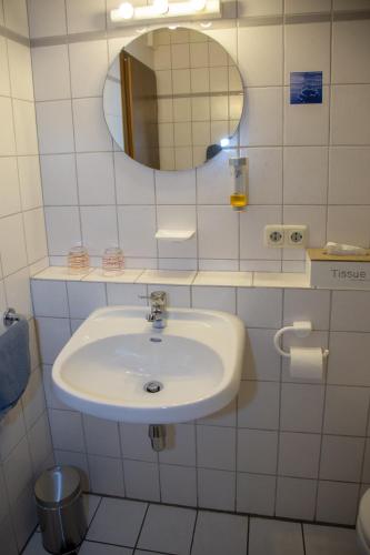 a white bathroom with a sink and a mirror at Weinhaus Kurtrierer Hof in Leiwen
