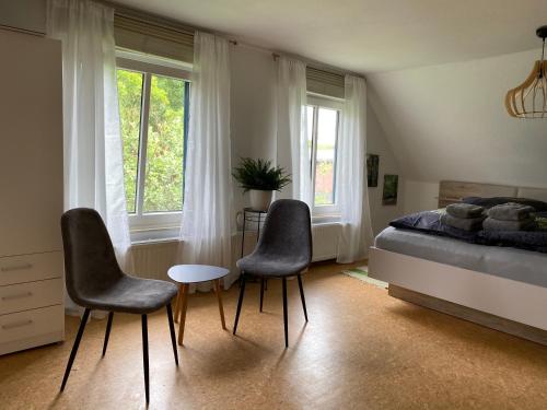 1 dormitorio con 2 sillas, 1 cama y 1 mesa en HUUS UTSPANN lichtdurchflutete FeWo im OG - 23 km vor Hamburg, en Seevetal