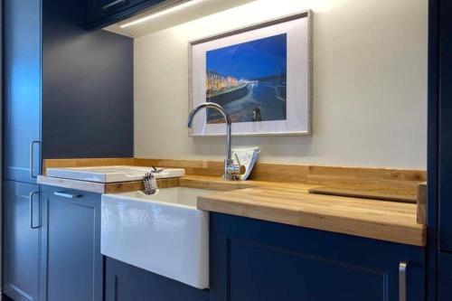 a kitchen with blue cabinets and a sink at WESTREACH Filey - a 4 Bedroom, all en-suite sleep 8 Townhouse in Filey