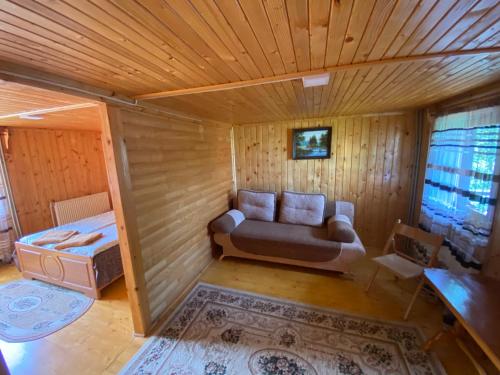 un soggiorno con divano in una camera in legno di Pid Playem a Volovets