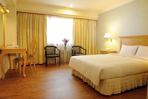 a hotel room with a bed and a desk and a window at Cambridge Tainan Hotel in Tainan