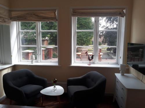 two chairs and a table in a room with three windows at Gutshof Rothensande in Waabs