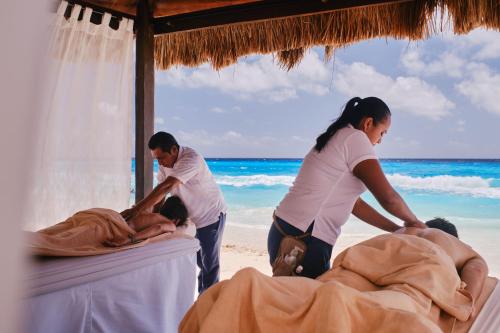 a group of people standing around a bed on the beach at Hotel NYX Cancun in Cancún