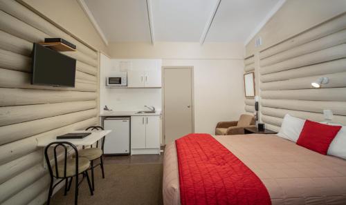 a bedroom with a bed and a table and a kitchen at Welcome Inn Motel Levin in Levin