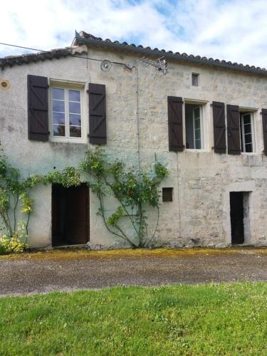 ein altes Steinhaus mit Fenstern und einer Tür in der Unterkunft Maison de campagne MONTCUQ en Quercy Blanc in Montcuq