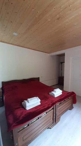 a bed with red sheets and white towels on it at Guest house-Lile in Mestia