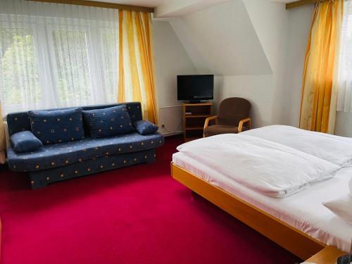 Landhotel "Wettin" في Neuhermsdorf: غرفة نوم بسرير واريكة وتلفزيون