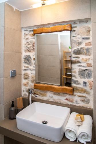a bathroom with a sink and a mirror and towels at Villa Kyani in Skopelos Town