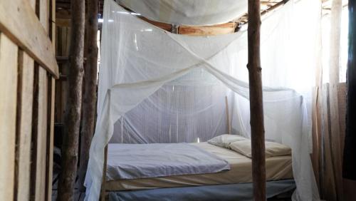 a bedroom with a canopy bed with a white mosquito net at Miguel Surf Camp in Quepos