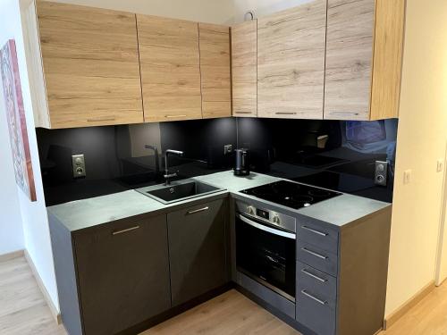 a kitchen with black and wooden cabinets and a sink at Très bel appartement T2 de standing entièrement meublé à 5 min à pied du centre. in Divonne-les-Bains