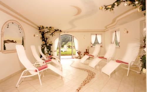 a salon with white chairs and a mirror at Garni La Majon in Selva di Val Gardena