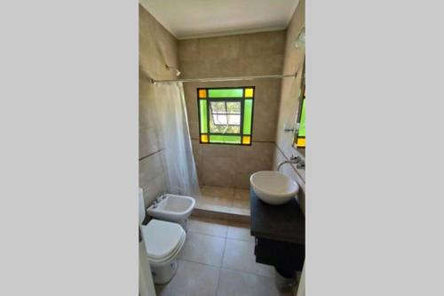 ein Bad mit einem Waschbecken, einem WC und einem Fenster in der Unterkunft Casa en Tierra de Sueños 3 in Roldán