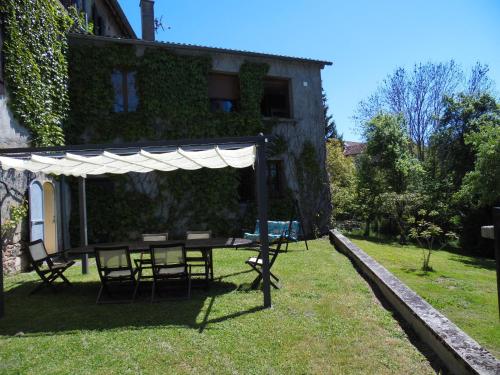 a table and chairs under a white umbrella in a yard at A l'Aube des Volcans in Charbonnières-les-Vieilles