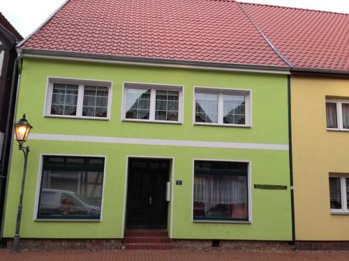 a green and yellow house with a red roof at Ferienwohnung Zur Glewe in Neustadt-Glewe