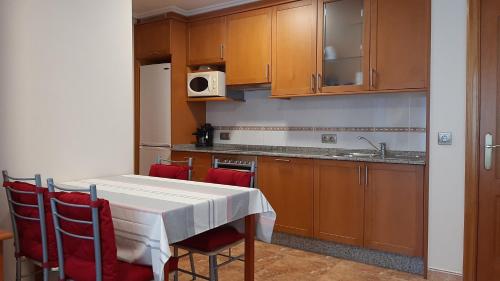 a kitchen with a white table and red chairs at Apartamento in Ferrol