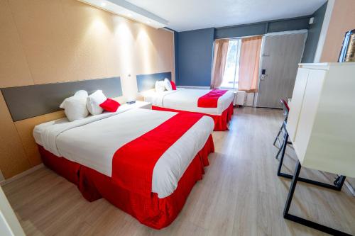 a hotel room with two beds with red and white sheets at Travelodge by Wyndham Orlando at Heart of International Drive in Orlando