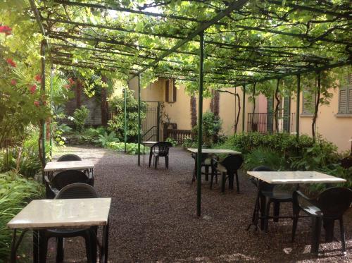 patio ze stołami i krzesłami pod pergolą w obiekcie Albergo Giardinetto w mieście Bellagio