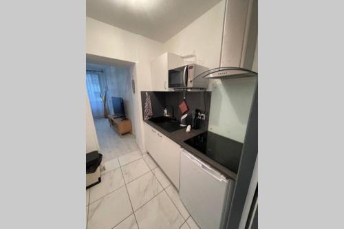 une cuisine avec des armoires blanches et un comptoir dans l'établissement Le petit pelet - Centre historique, proche Halles de Niort, port Boinot, moulin du Roc - 2 mn hyper centre, Wifi et Netflix, à Niort