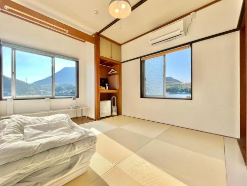 1 dormitorio con 1 cama y ventanas grandes en 島宿Nest, en Onomichi