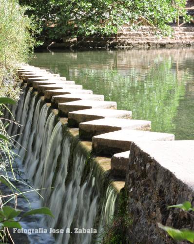 a stone bridge over a river with water at Casa Rural Los Parrales in El Tranco