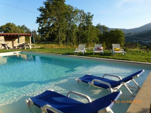 einem Pool mit zwei blauen Stühlen und einer Gruppe in der Unterkunft Quinta da Aranha in Arcos de Valdevez