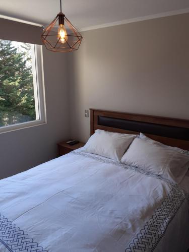 a bedroom with a white bed with a window at Departamento en Pucón in Pucón