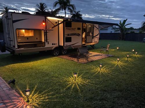 an rv parked in a yard with lights in the grass at Cozy Camper - Free Parking in Miami
